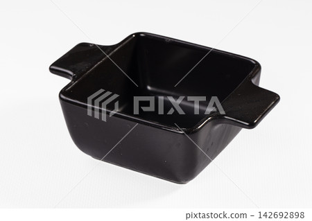 Empty black ceramic square baking dish or ramekin with small handles, isolated on clean white background, high angle view for food preparation Empty black ceramic square baking dish or ramekin with small handles, isolated on clean white background, high angle view for food preparation 142692898