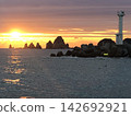 The lighthouse begins to shine with the light of the rising sun. 142692921