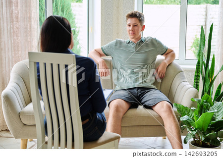Teenage boy talking to female therapist during counseling session in office Teenage boy talking to female therapist during counseling session in office 142693205