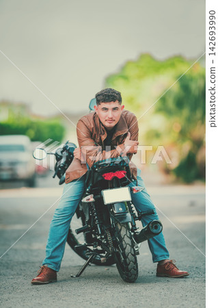 Portrait of a handsome motorcyclist leaning against his motorcycle and looking at the camera Portrait of a handsome motorcyclist leaning against his motorcycle and looking at the camera 142693990