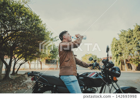 Male motorcyclist drinking water on the road. Male motorcyclist drinking water on the road. 142693998