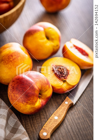 Fresh Ripe nectarines On Wooden Table With Cut Halves Showing Stone And Juicy Flesh Fresh Ripe nectarines On Wooden Table With Cut Halves Showing Stone And Juicy Flesh 142694152