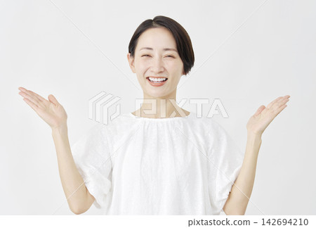 A middle-aged woman points left and right with her palms against a white background. A middle-aged woman points left and right with her palms against a white background. 142694210