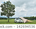 Auto camping next to a single tree in a grassy field Auto camping next to a single tree in a grassy field 142694536