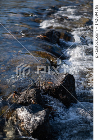 The river rushed over the rocks, creating a spray of mist in the bright sunlight. The spray sparkled in the sun, creating a beautiful sight. The river rushed over the rocks, creating a spray of mist in the bright sunlight. The spray sparkled in the sun, creating a beautiful sight. 142694568