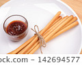 pack of breadsticks with ketchup dipping sauce in white dish on wood table 142694577