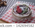 a basque burnt cheesecake topping with strawberry and rosemary serving on dish with crumpled paper 142694582