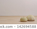 two sea urchin skeletons put on wood table with blurred concrete wall background in warm tone color 142694588