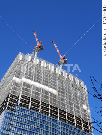 A high-rise building under construction at Tokyo Station's Yaesu Exit, set against a winter blue sky. A high-rise building under construction at Tokyo Station's Yaesu Exit, set against a winter blue sky. 142695615