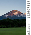 富士山沐浴在紅色的燈光下，周圍是一片綠茵的草坪。 142697316