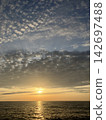 The cirrocumulus clouds bid farewell to the setting sun sinking into the sea, with a sense of bittersweet loss. 142697488