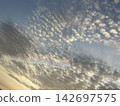 Cirrocumulus clouds chasing the sun as it sinks below the horizon 142697575