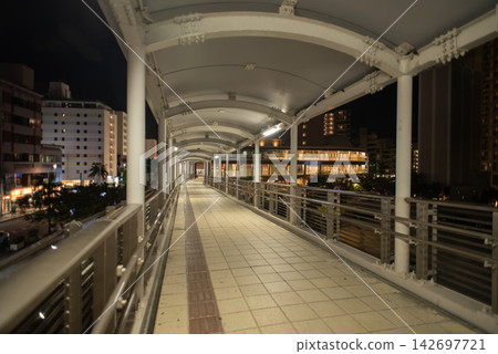 A covered walkway leading to buildings in the city at night A covered walkway leading to buildings in the city at night 142697721