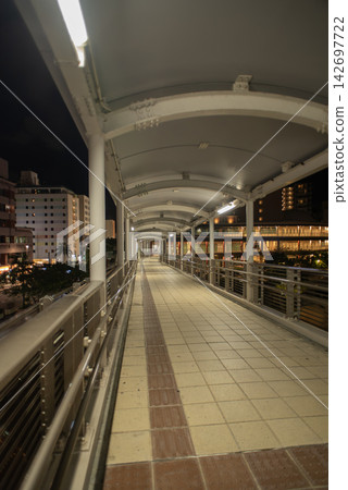 A covered walkway leading to buildings in the city at night A covered walkway leading to buildings in the city at night 142697722