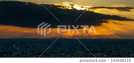 Divine rays of light pour down from between the clouds of the setting sun onto the Tokyo cityscape and the distant mountain range. Divine rays of light pour down from between the clouds of the setting sun onto the Tokyo cityscape and the distant mountain range. 142698519