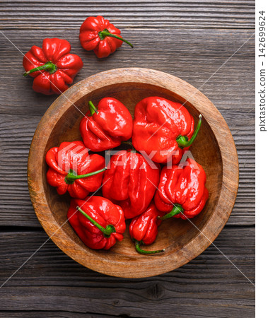 Red habanero peppers in bowl on wooden table top view Red habanero peppers in bowl on wooden table top view 142699624