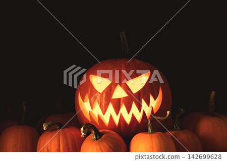 Scary glowing pumpkin face emerging from a harvest Scary glowing pumpkin face emerging from a harvest 142699628