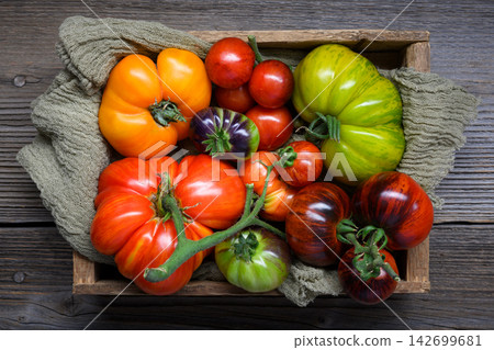 Wooden crate with colorful heirloom tomatoes on burlap cloth Wooden crate with colorful heirloom tomatoes on burlap cloth 142699681