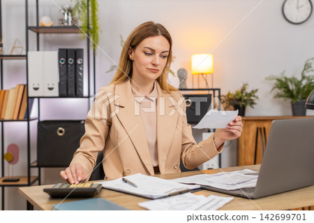 Businesswoman sorts receipts uses calculator balances budget signs final contract with pleased smile Businesswoman sorts receipts uses calculator balances budget signs final contract with pleased smile 142699701