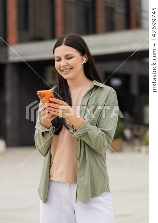 Young woman making video call walking in city street smiling and waving during smartphone vlog clip Young woman making video call walking in city street smiling and waving during smartphone vlog clip 142699745