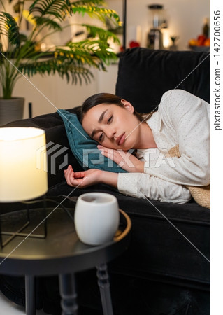Young woman exhausted after work lies on pillow closes eyes falls asleep stress fades sleepy night Young woman exhausted after work lies on pillow closes eyes falls asleep stress fades sleepy night 142700656