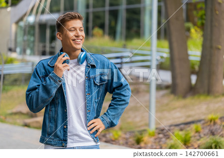 Young man smiling calmly at camera while walking in city street with relaxed portrait and calm mood Young man smiling calmly at camera while walking in city street with relaxed portrait and calm mood 142700661