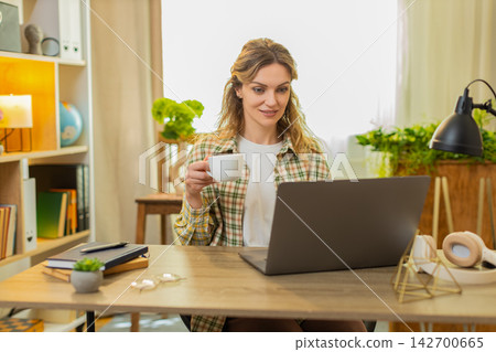 Young woman on home table planning daily schedule with coffee cup and laptop for productive morning Young woman on home table planning daily schedule with coffee cup and laptop for productive morning 142700665