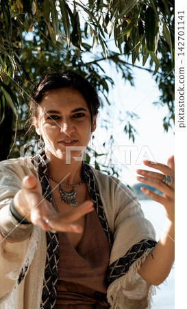 A beautiful brunette dressed in boho style meditates and dances in the forest. A magical ritual takes place against a green forest backdrop. 142701141