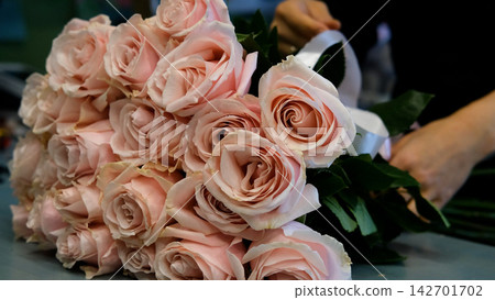 Female florist arranges delicate bouquet of pink alstroemeria flowers. Flower delivery. Small business concept Female florist arranges delicate bouquet of pink alstroemeria flowers. Flower delivery. Small business concept 142701702