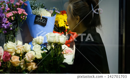 Beautiful white roses in a flower shop. Florist assembles a bouquet to order Beautiful white roses in a flower shop. Florist assembles a bouquet to order 142701703