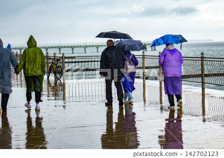 Tourists exploring new city despite heavy rain using umbrellas and raincoats for water protection. Bad weather does not stop travel concept. Rainy day travel hacks Tourists exploring new city despite heavy rain using umbrellas and raincoats for water protection. Bad weather does not stop travel concept. Rainy day travel hacks 142702123