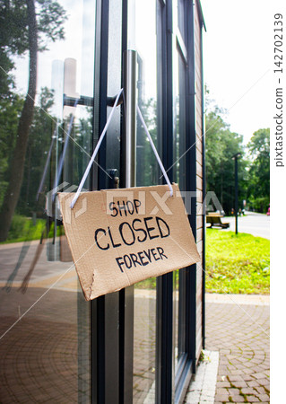 CLOSED sign hanging on small shop door. Small business shutting down due to financial crisis. Local business unable to survive economic pressure CLOSED sign hanging on small shop door. Small business shutting down due to financial crisis. Local business unable to survive economic pressure 142702139