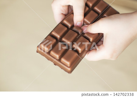 Kid hands holding and bending chocolate bar Kid hands holding and bending chocolate bar 142702338