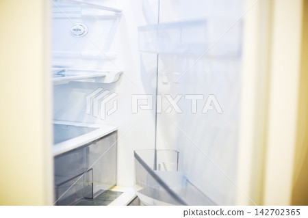 Empty refrigerator interior showing white shelves and lack of food 142702365