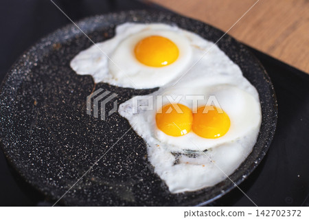 Frying sunny side up eggs with double yolk in pan Frying sunny side up eggs with double yolk in pan 142702372