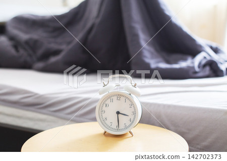 Alarm clock on bedside table nearing wake up time 142702373