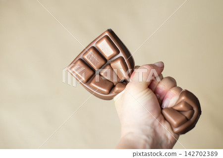Child's hand pressing a colorful squishy chocolate stress toy on beige background Child's hand pressing a colorful squishy chocolate stress toy on beige background 142702389