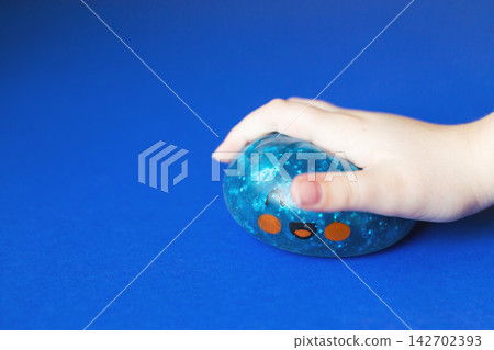 Child's hand squeezing blue stress ball for anxiety relief Child's hand squeezing blue stress ball for anxiety relief 142702393