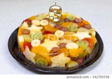 A homemade cake overflowing with fruit to celebrate a 3rd birthday. A homemade cake overflowing with fruit to celebrate a 3rd birthday. 142703336