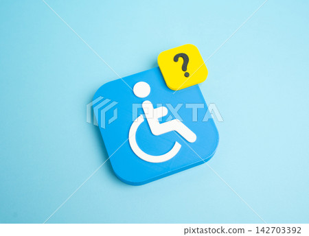 A disability symbol and a question mark. Explanation of rights and rules, benefits and social compensations. A document package for obtaining status. Concept of social awareness. A disability symbol and a question mark. Explanation of rights and rules, benefits and social compensations. A document package for obtaining status. Concept of social awareness. 142703392