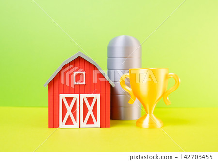 A farm barn and a golden winner's cup. Concept of agricultural success and achievement. Symbol of farming excellence, competition, quality and rural prosperity. A farm barn and a golden winner's cup. Concept of agricultural success and achievement. Symbol of farming excellence, competition, quality and rural prosperity. 142703455