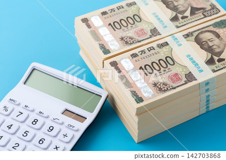 一疊1000萬日元鈔票和一個白色計算器 一疊1000萬日元鈔票和一個白色計算器 142703868