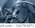 Finishing cut on a metal shaft part using a lathe machine with liquid coolant in light blue tone 142703871