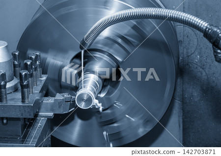 Finishing cut on a metal shaft part using a lathe machine with liquid coolant in light blue tone Finishing cut on a metal shaft part using a lathe machine with liquid coolant in light blue tone 142703871