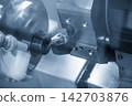 Close-up of a CNC lathe face cutting a metal ring part in a blue tone scene 142703876