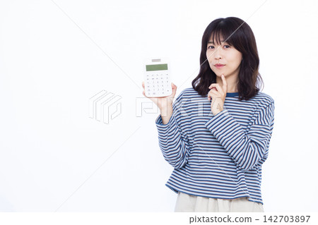 一位女士面帶微笑,手裡拿著計算器,似乎在思考。 一位女士面帶微笑,手裡拿著計算器,似乎在思考。 142703897