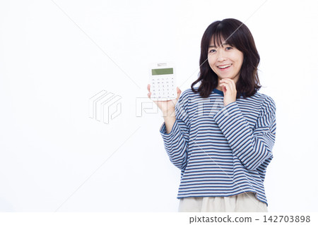 一位女士面帶微笑,手裡拿著計算器,似乎在思考。 一位女士面帶微笑,手裡拿著計算器,似乎在思考。 142703898