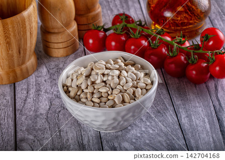 White beans in textured ceramic bowl with cherry tomatoes on vine, wooden salt mill and pepper grinder, saffron in glass jar on grey wood table White beans in textured ceramic bowl with cherry tomatoes on vine, wooden salt mill and pepper grinder, saffron in glass jar on grey wood table 142704168