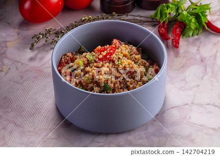 Quinoa salad with diced tomatoes, fresh herbs and red chili peppers in a matte gray bowl on textured surface Quinoa salad with diced tomatoes, fresh herbs and red chili peppers in a matte gray bowl on textured surface 142704219