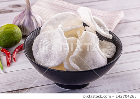 Crispy white pork rinds in black ceramic bowl with garlic lime and red chili peppers on rustic white wood table Crispy white pork rinds in black ceramic bowl with garlic lime and red chili peppers on rustic white wood table 142704263
